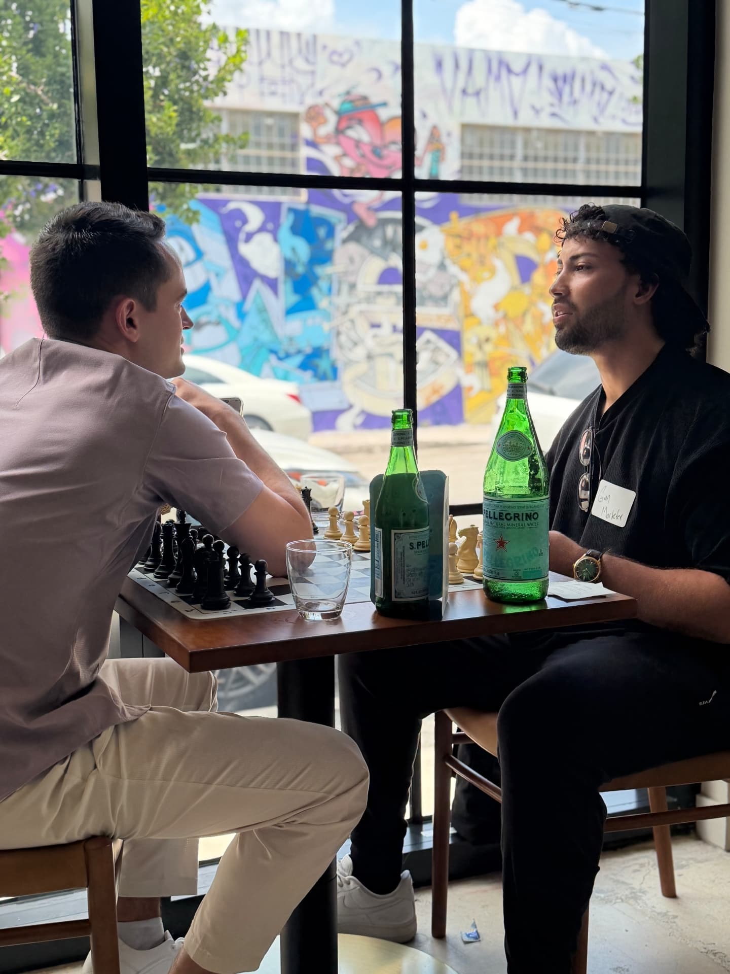 Two guests playing chess by a sunlit window at a Convive event