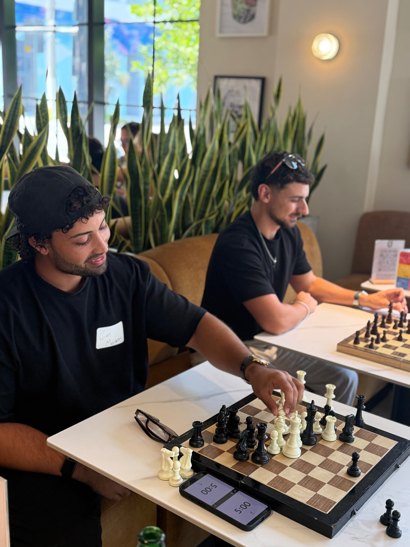 Two guests leaning over a chess board mid-conversation
